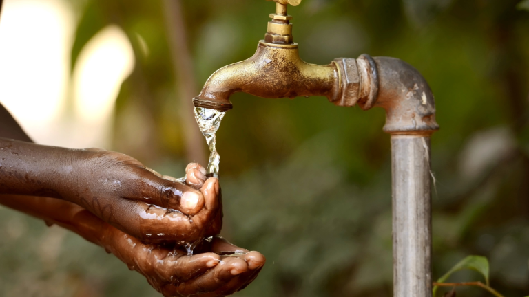 Hands washing under a tap with running water as a symbol of water harvesting and management by Ambokili Farm